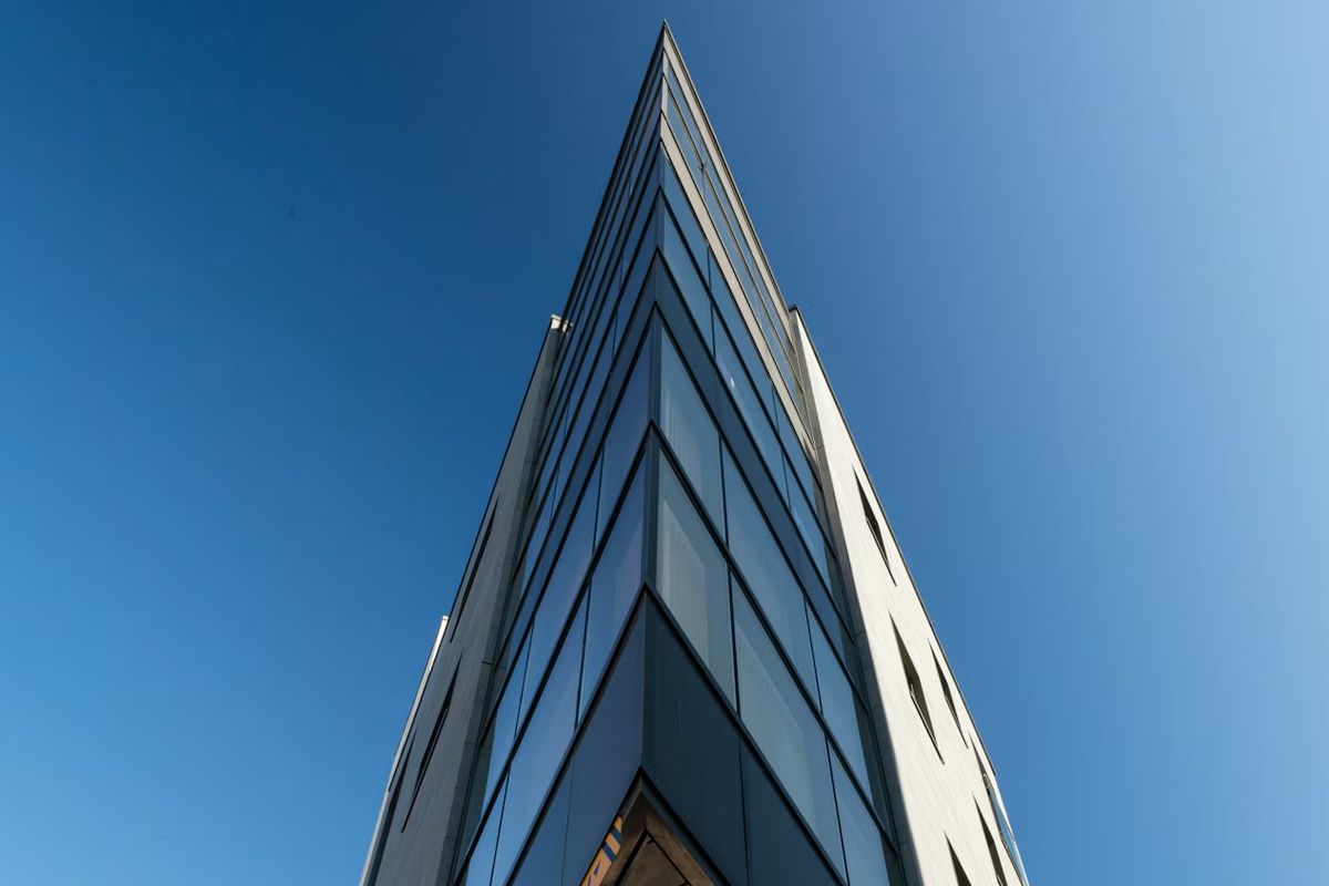The sharp-angled glass corner of the building at Liberation Station, St Helier, Jersey, Channel Islands, against a blue sky.
