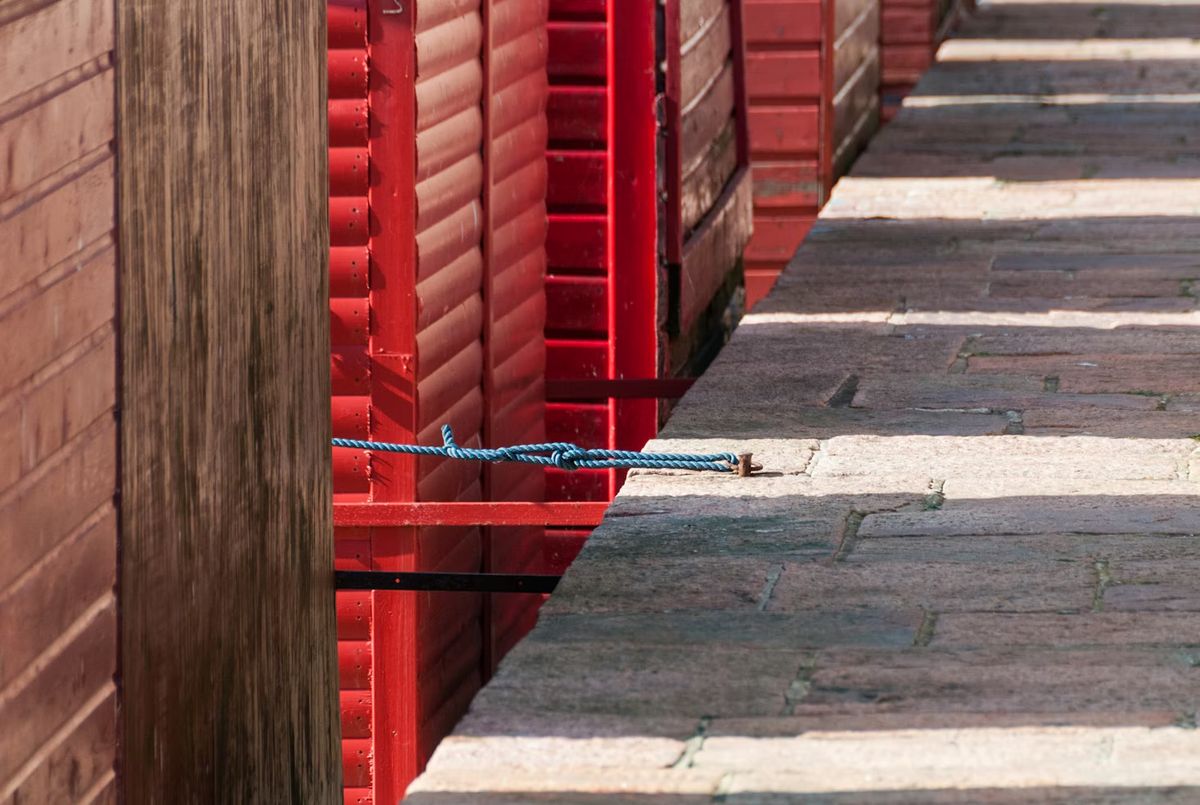 A row of red wooden fishing huts on the granite pier at Bonne Nuit Bay, St John, Jersey, Channel Islands.